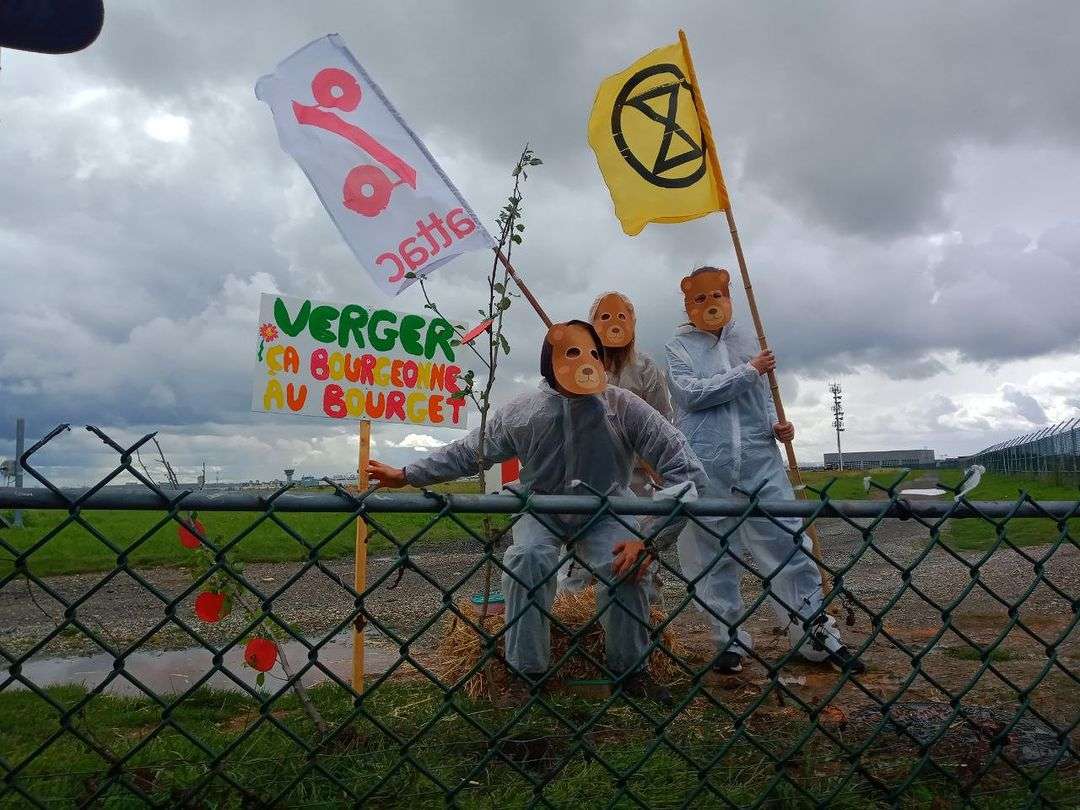 Activists wearing animal masks and holding Attac and XR flags